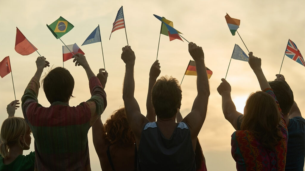 Begreppet internationella relationer. Människor med olika flaggor. Morgon himmel som bakgrund.